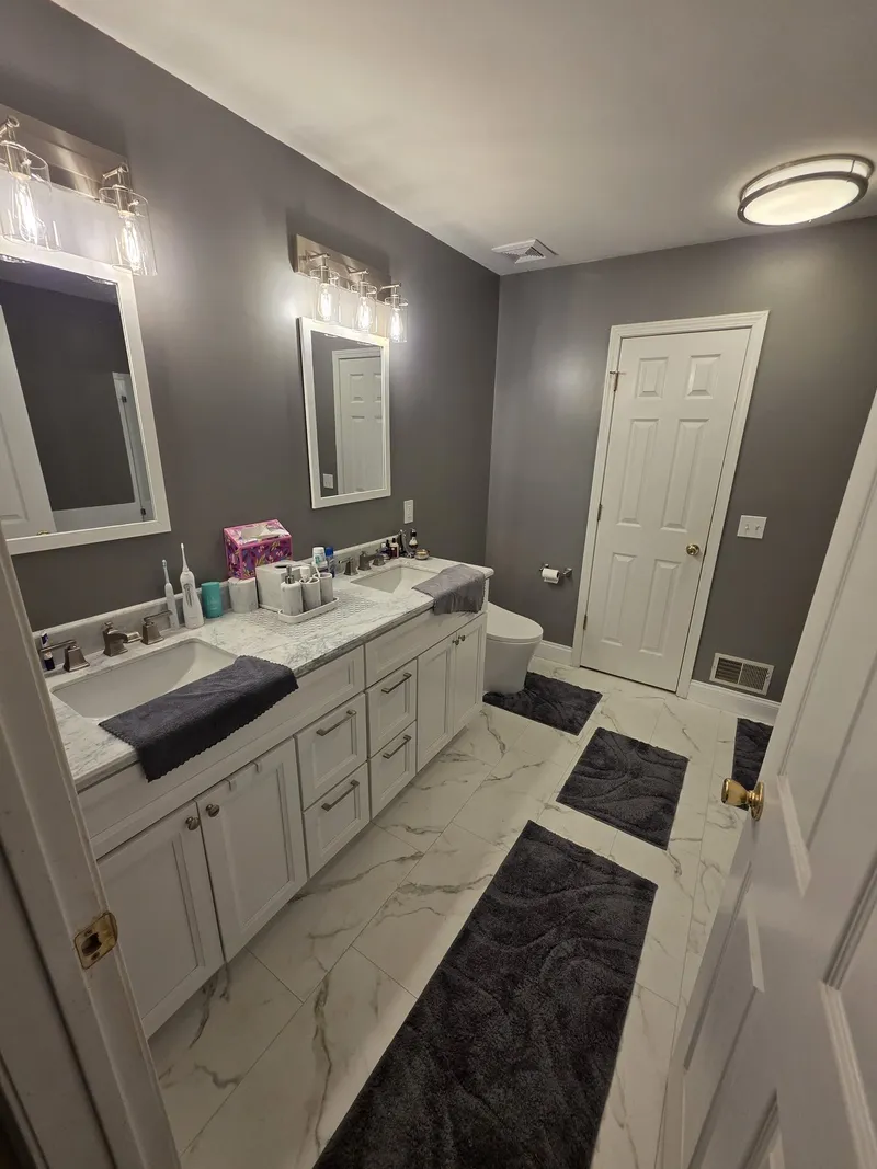 A bathroom with charcoal walls, a white vanity and a marble floor