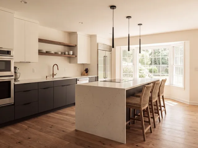 A modern kitchen with charcoal cabinets, a quartz waterfall island and walnut open shelving