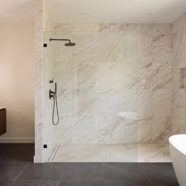 A primary bathroom in warm stone, walnut and matte black, built to the TrueLevel standard